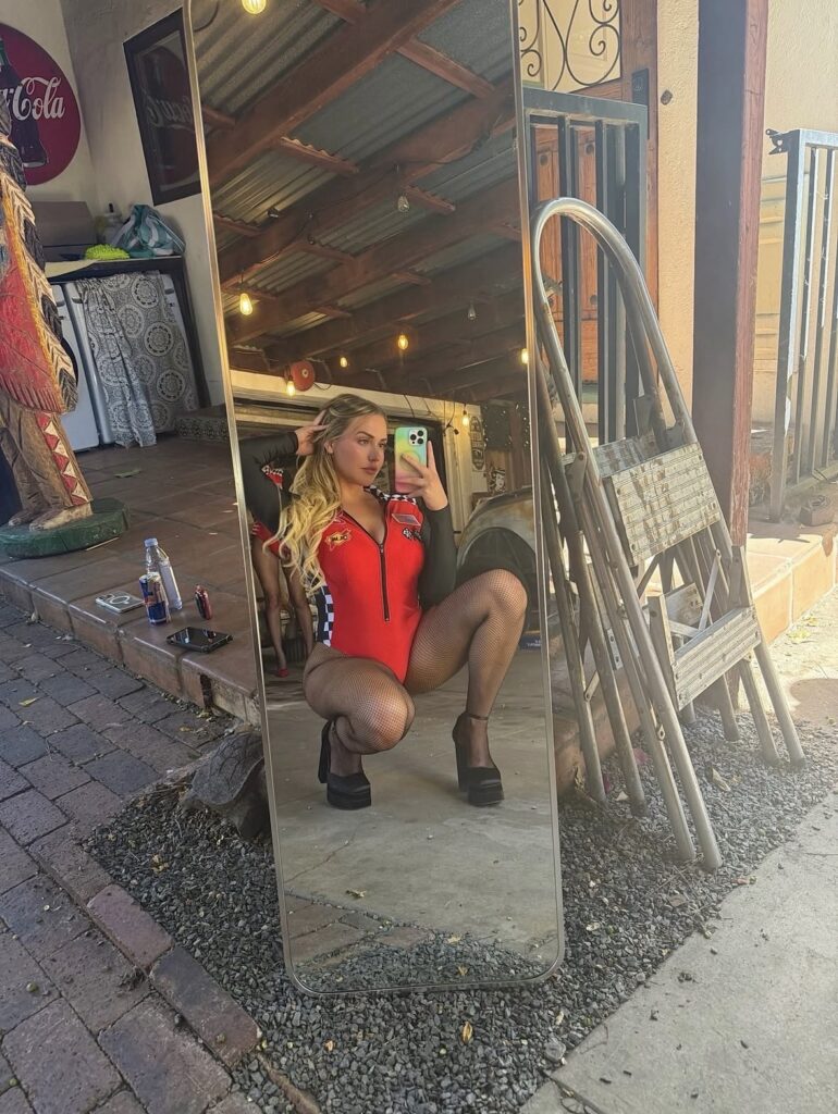 Mia Malkova blonde mirror selfie in red racing-inspired outfit with glamorous influencer aesthetic